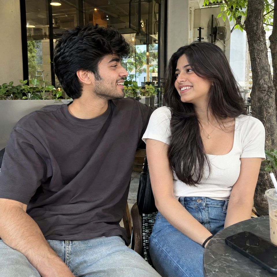 A couple laughing across a café table, turned towards each other