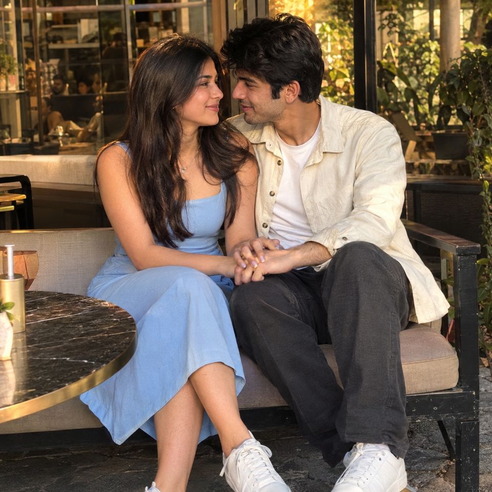 A couple on a café bench, holding hands and looking at each other